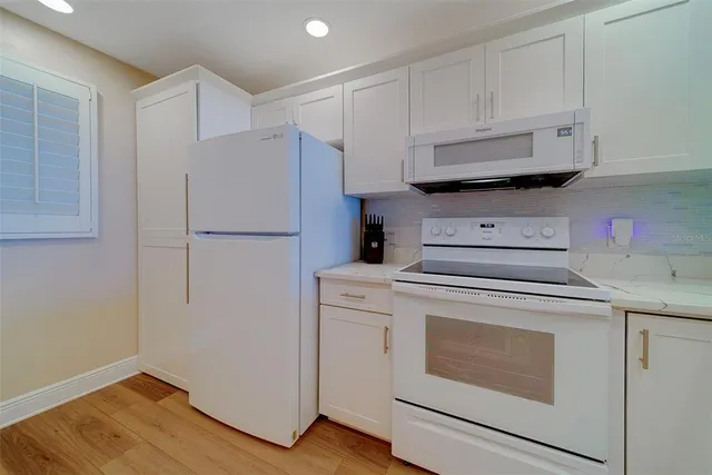 a kitchen with white cabinets and white appliances