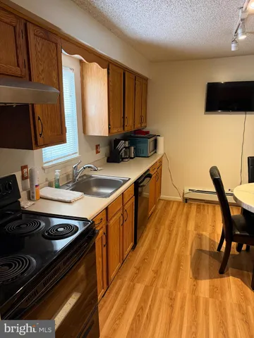 a kitchen with a sink a stove and wooden floor