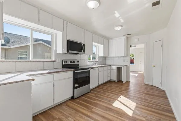 a kitchen with granite countertop a stove top oven sink and cabinets