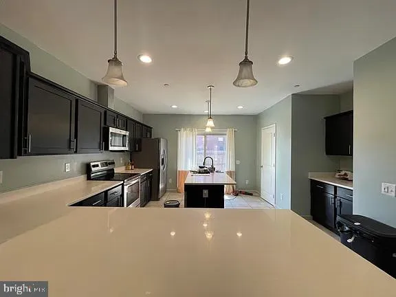 a large kitchen with stainless steel appliances a large counter top a stove and a refrigerator