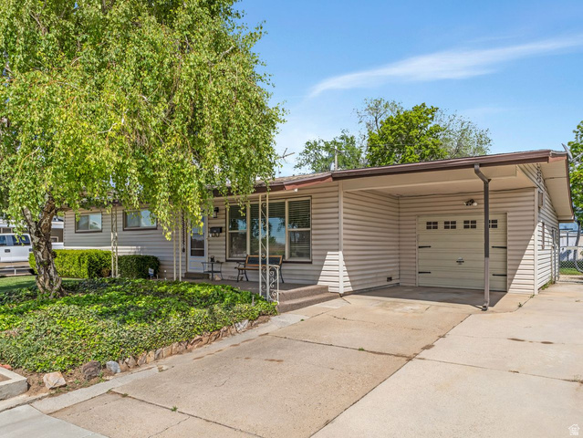 1502 North 475 West Sunset, UT 84015 - Photo 3 of 23 Single-story residence featuring light-toned horizontal siding, an attached single-car garage with overhead door, and a covered carport