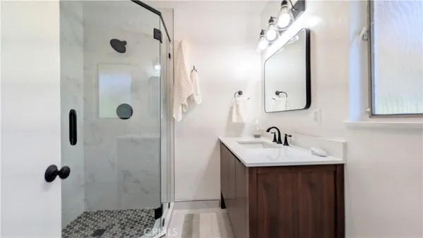 a bathroom with a sink and mirror with shower