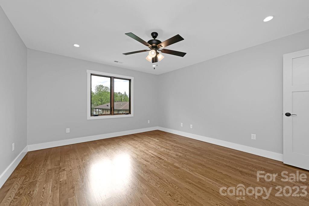 183 Neely Road Brevard, NC 28712 - Photo 30 of 44 an empty room with wooden floor ceiling fan and windows