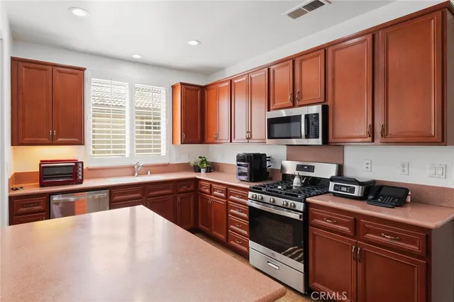 a kitchen with stainless steel appliances granite countertop wooden cabinets a stove top oven a sink and dishwasher