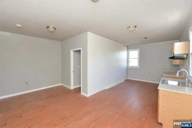 a view of empty room with window and wooden floor