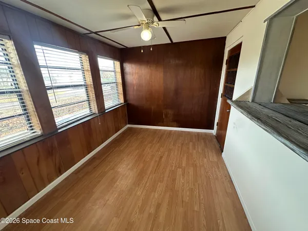 a view of empty room with wooden floor and fan
