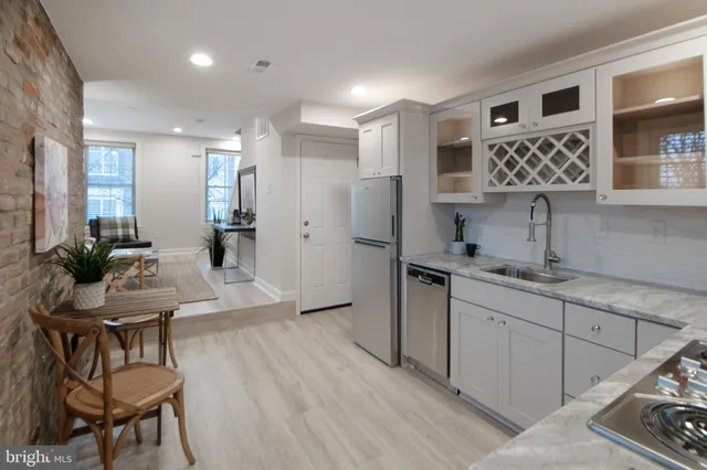 a living room with couches and kitchen view with wooden floor