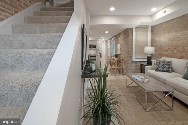 a kitchen with stainless steel appliances a microwave a stove a refrigerator and a dining table with wooden floor