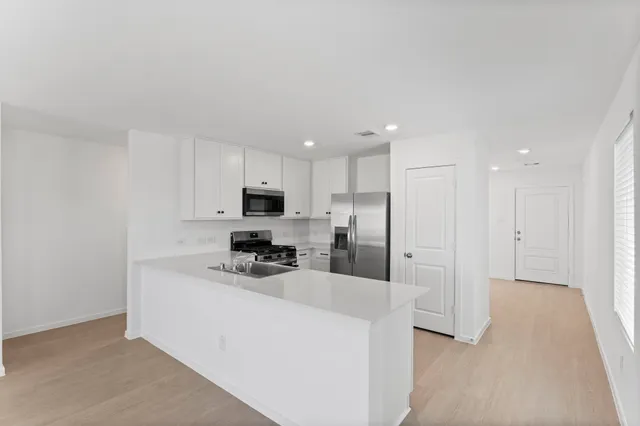 a kitchen with stainless steel appliances a stove a sink and a refrigerator