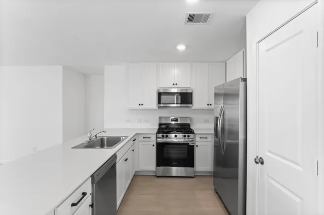 a kitchen with stainless steel appliances granite countertop a sink a stove and a refrigerator