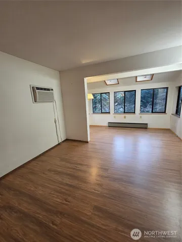 a view of a big room with wooden floor and windows