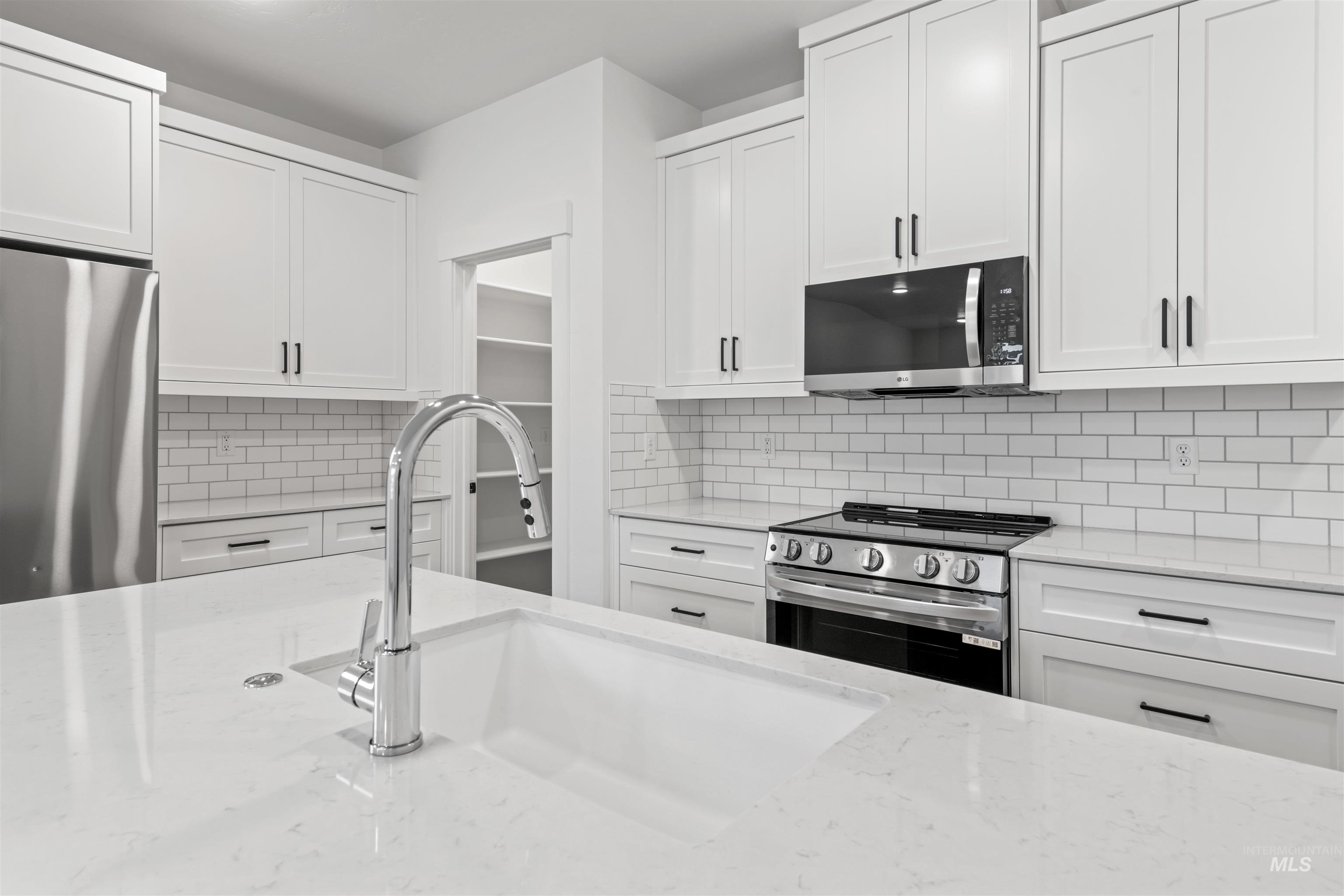 6369 South Sachet Avenue Meridian, ID 83642 - Photo 2 of 13 Kitchen with stainless steel appliances, white cabinets, backsplash, and light stone counters