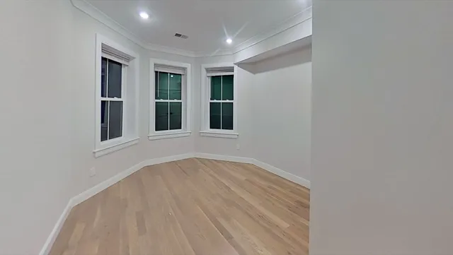 a view of an empty room with wooden floor and windows