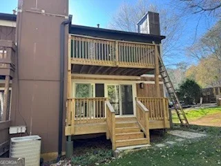 a view of a house with a deck and a yard with wooden fence