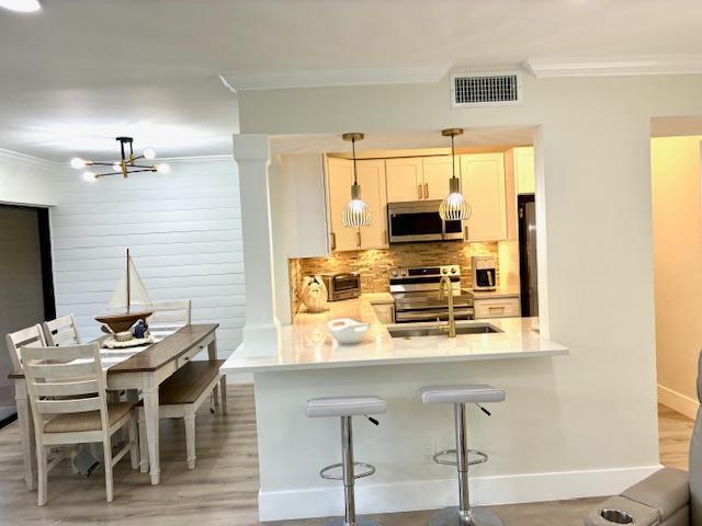 a kitchen with stainless steel appliances kitchen island granite countertop a table chairs and a refrigerator