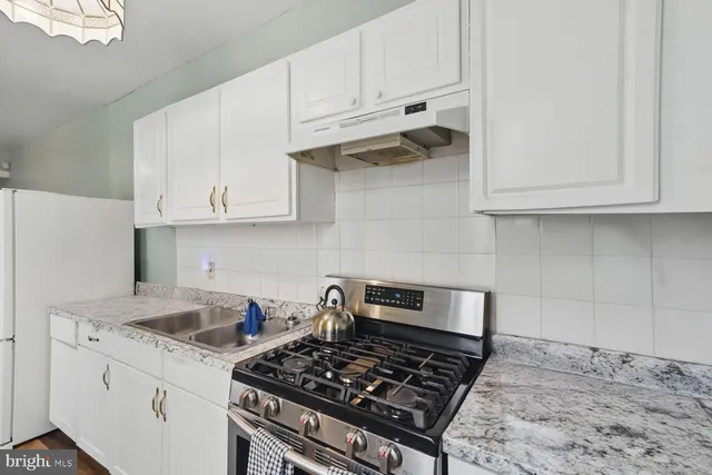 a kitchen with white cabinets and a stove top oven