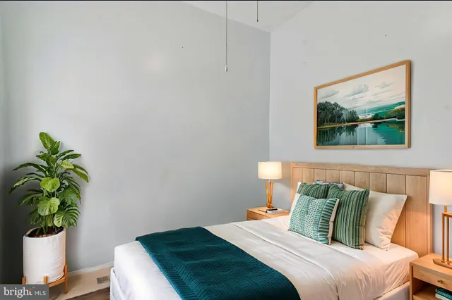 a bed sitting in a bedroom next to a window with potted plant