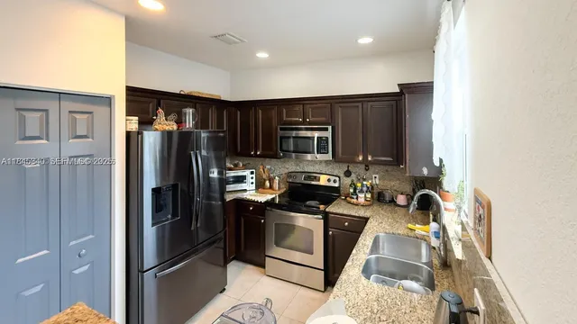 a kitchen with stainless steel appliances granite countertop a sink and a refrigerator