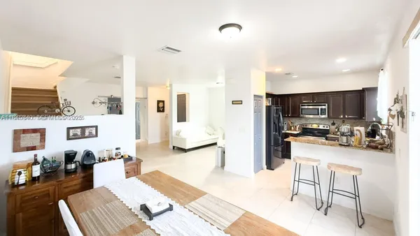 a room with stainless steel appliances kitchen island granite countertop a refrigerator and cabinets
