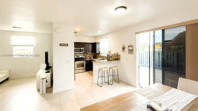 a room with stainless steel appliances kitchen island granite countertop a refrigerator and cabinets