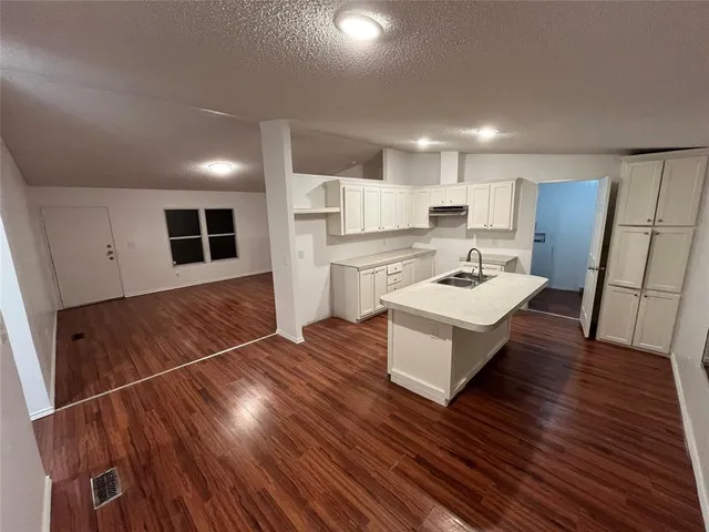 a living room with stainless steel appliances furniture and a wooden floor