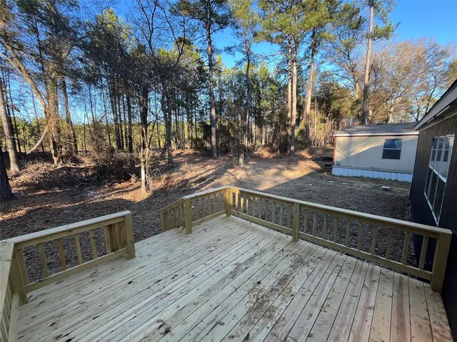 a view of a balcony with wooden floor and trees