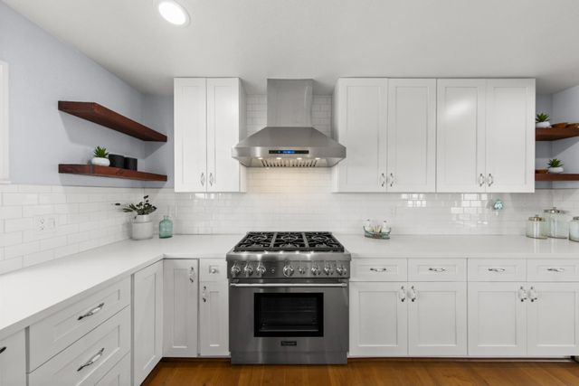 a kitchen with granite countertop white cabinets and a stove