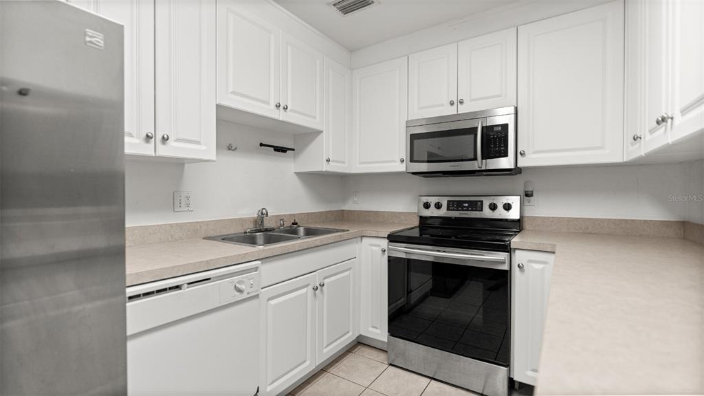 501 Southwest 75th Street, Unit B5 Gainesville, FL 32607 - Photo 10 of 38 a kitchen with granite countertop white cabinets and stainless steel appliances