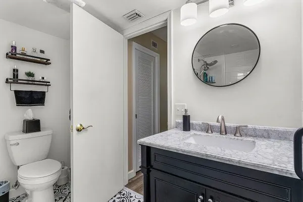 a bathroom with a granite countertop toilet sink and mirror