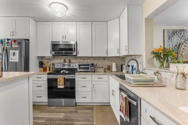 a kitchen with kitchen island granite countertop a sink stainless steel appliances and white cabinets
