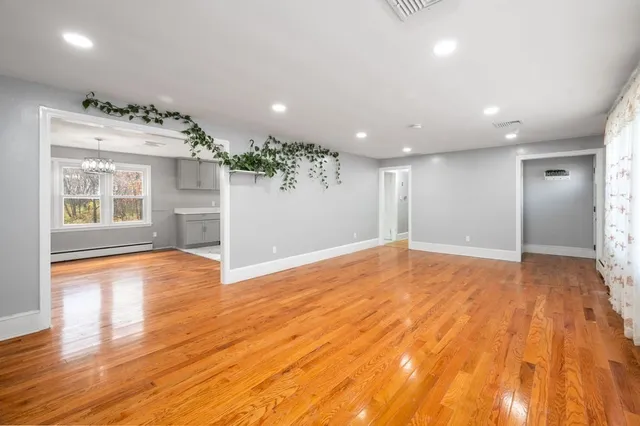 a view of an empty room with a window and wooden floor