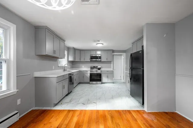 a view of empty room with wooden floor and chandelier