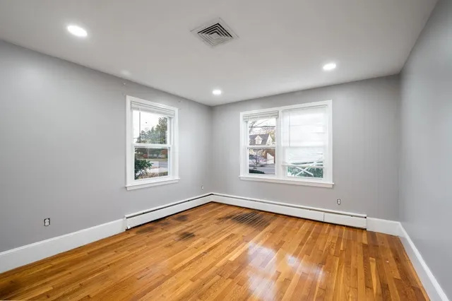 a view of empty room with wooden floor and fan