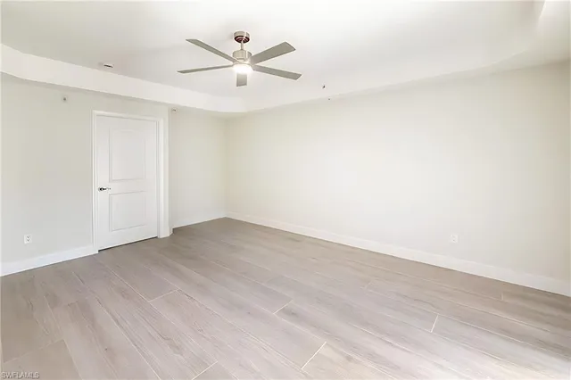 an empty room with wooden floor and a ceiling fan