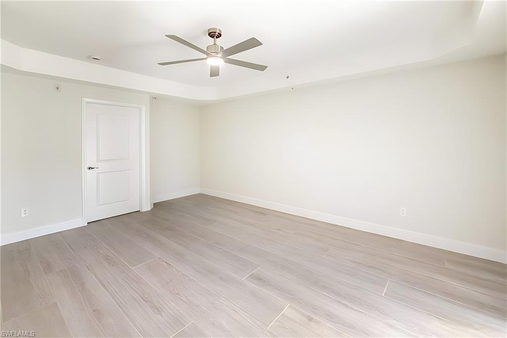 1100 Pine Ridge Road, Unit A106 Naples, FL 34108 - Photo 11 of 27 an empty room with wooden floor and a ceiling fan