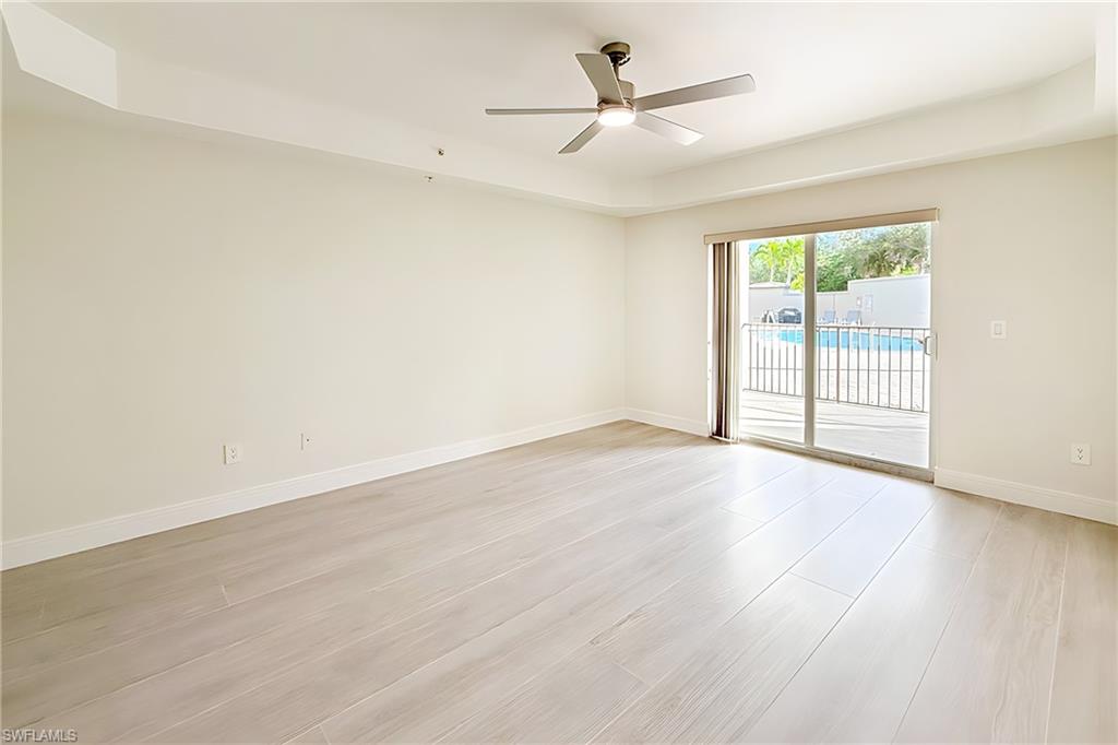1100 Pine Ridge Road, Unit A106 Naples, FL 34108 - Photo 12 of 27 an empty room with wooden floor and windows