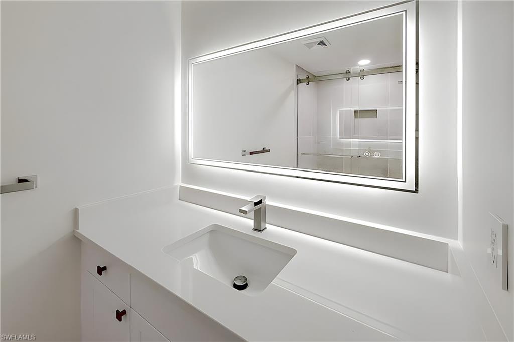 1100 Pine Ridge Road, Unit A106 Naples, FL 34108 - Photo 15 of 27 a bathroom with a sink and mirror