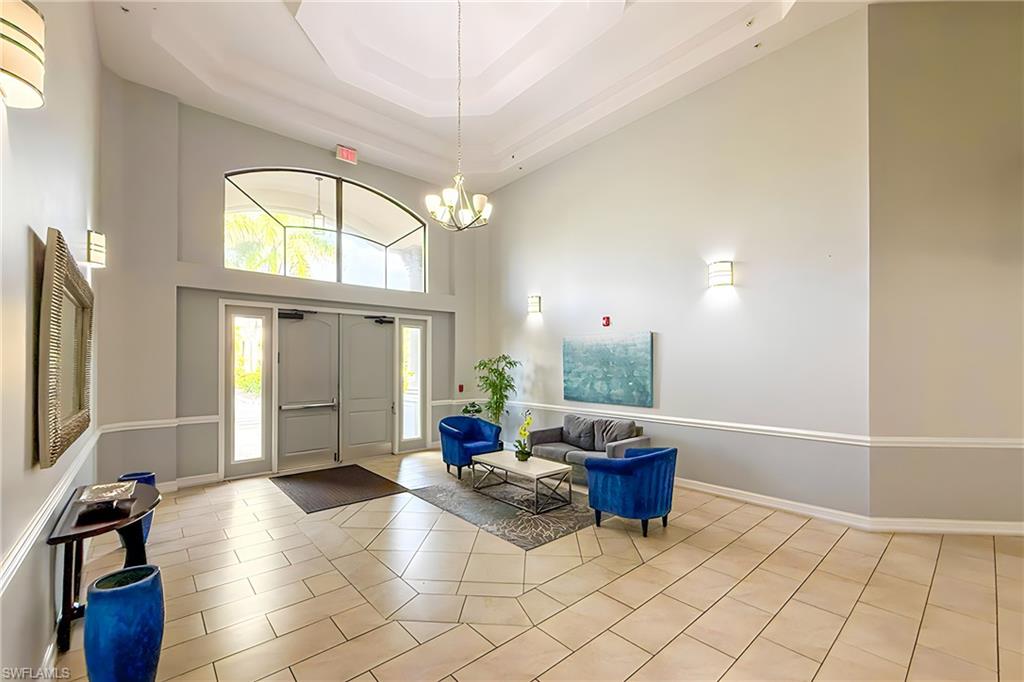 1100 Pine Ridge Road, Unit A106 Naples, FL 34108 - Photo 21 of 27 a living room with furniture a flat screen tv and a large window