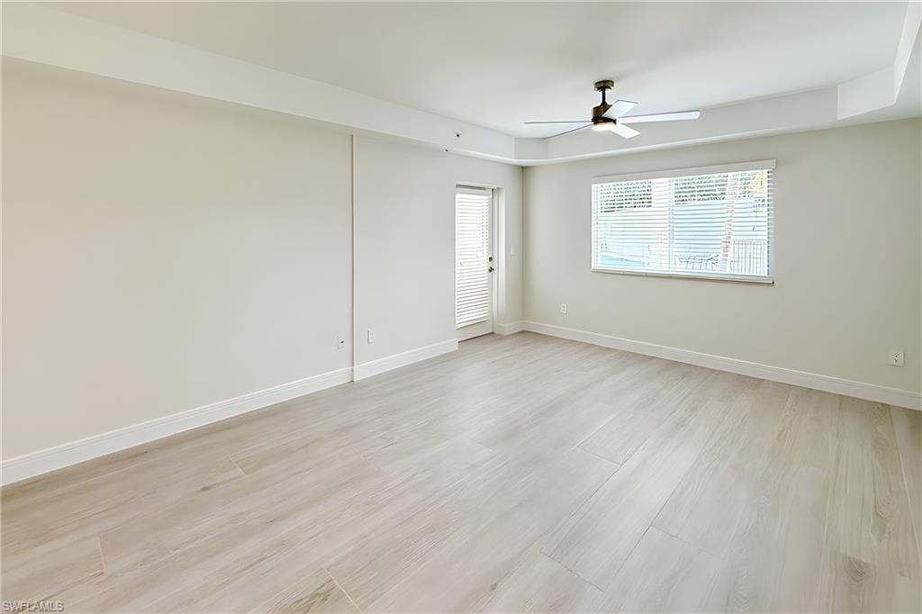 1100 Pine Ridge Road, Unit A106 Naples, FL 34108 - Photo 7 of 27 a view of an empty room with wooden floor and a window