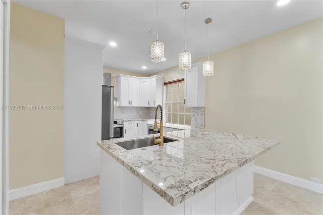 a kitchen with granite countertop a sink a center island and stainless steel appliances
