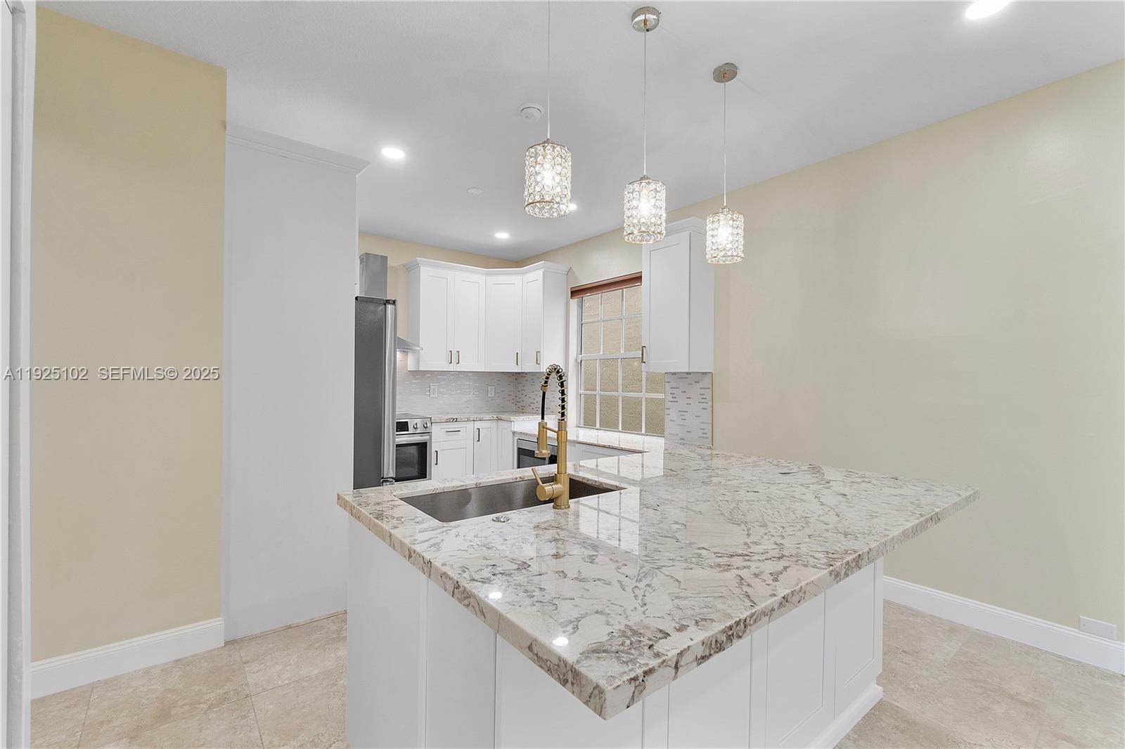 5310 Northwest 124th Way Coral Springs, FL 33076 - Photo 4 of 30 a kitchen with granite countertop a sink a center island and stainless steel appliances