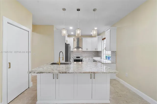 a kitchen with kitchen island granite countertop a sink cabinets and stainless steel appliances