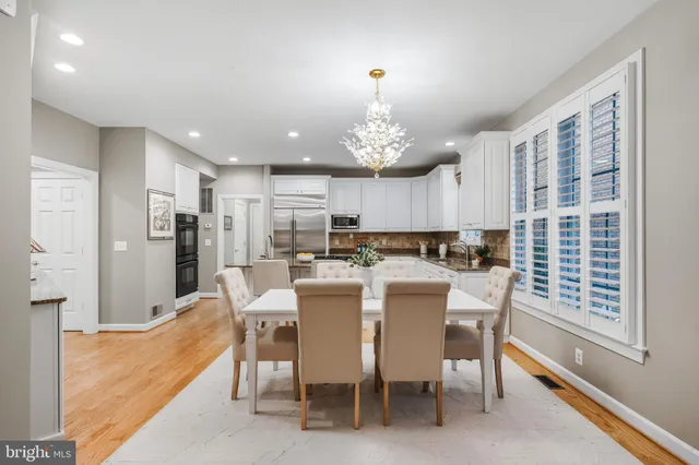 a kitchen with stainless steel appliances granite countertop a stove top oven a sink a refrigerator and white cabinets with wooden floor