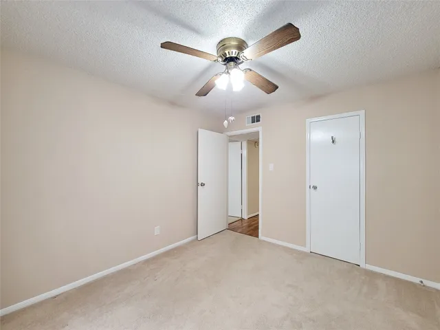 a view of an empty room and chandelier fan