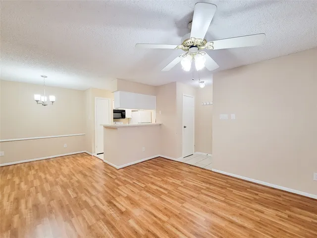 a view of empty room with wooden floor and ceiling fan