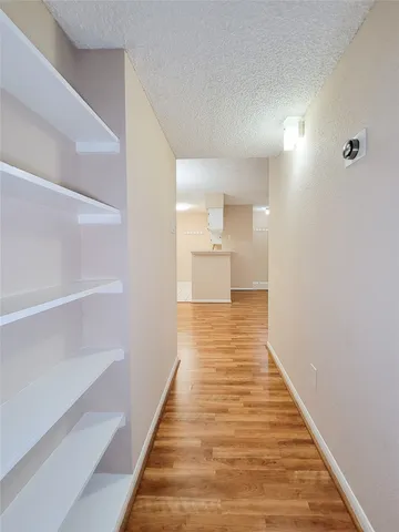 a view of a hallway with wooden floor and a bathroom