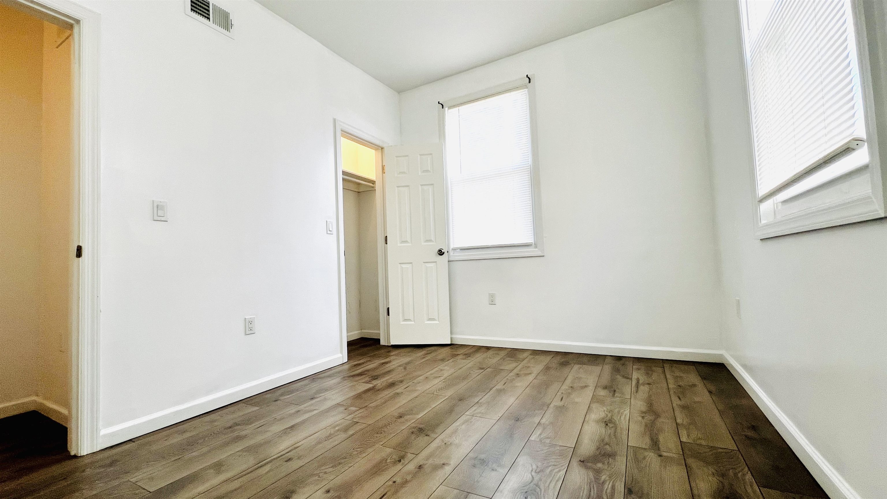 473 Grove Street, Unit 1 Irvington, NJ 07111 - Photo 7 of 9 an empty room with wooden floor and windows