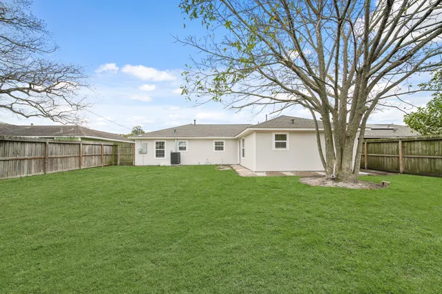 a view of a yard in front of a house with large trees