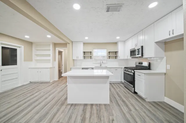 a large kitchen with stainless steel appliances granite countertop a stove and a sink