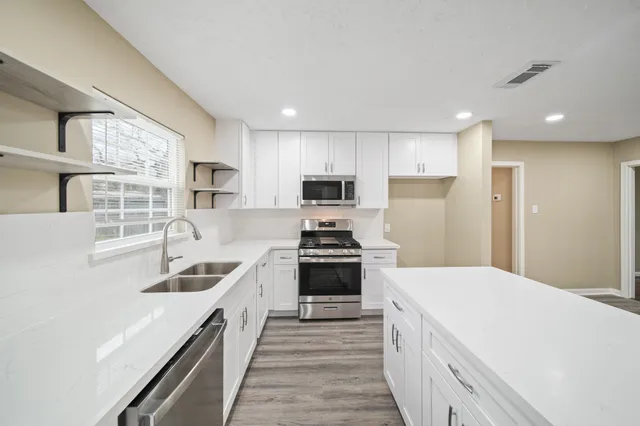 a kitchen with kitchen island granite countertop a sink and appliances